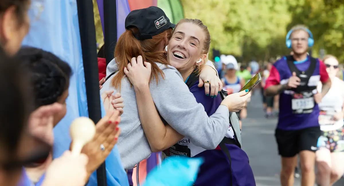 Two people hugging each other at a marathon.