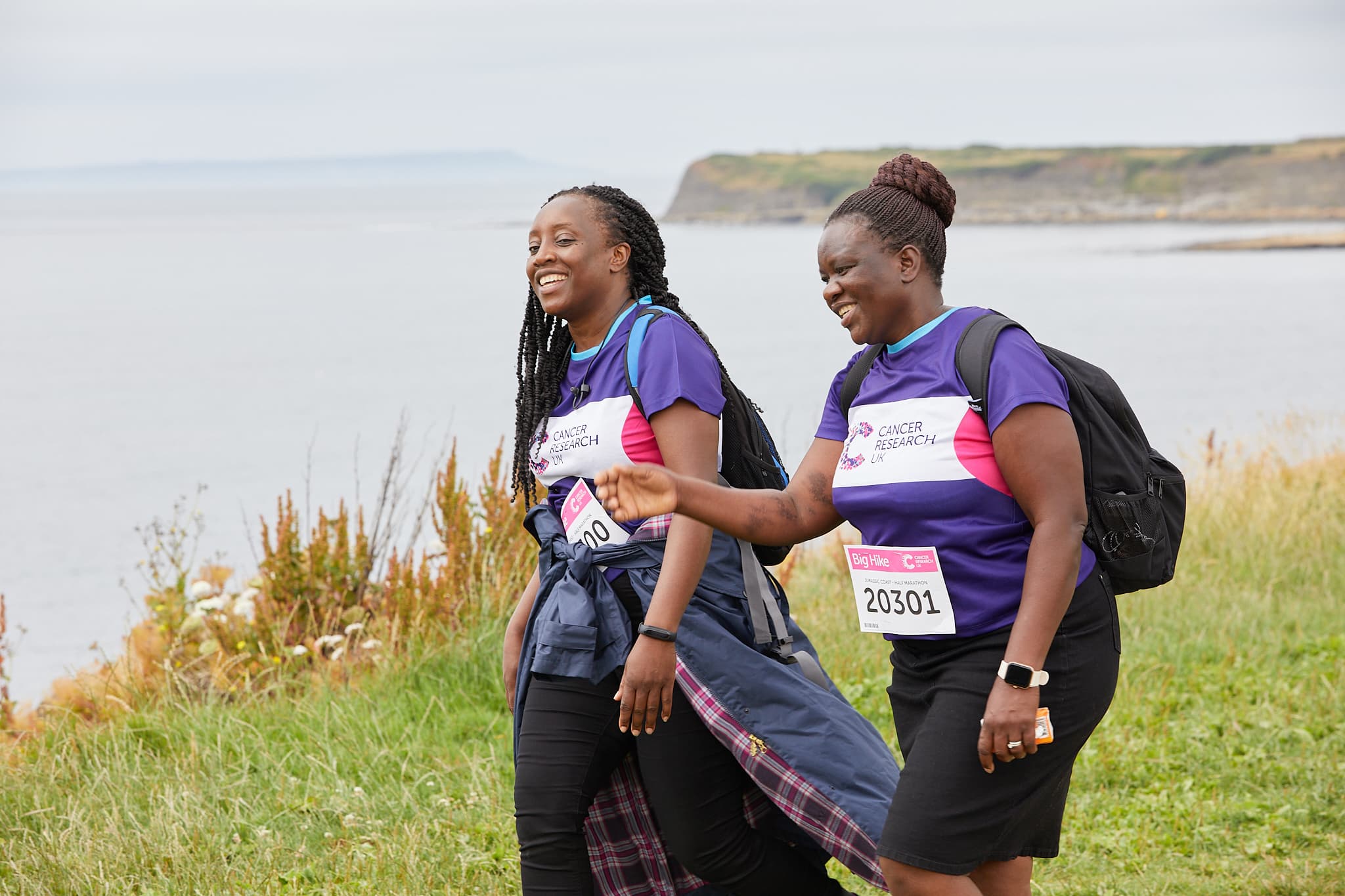 two women along a coastal line laughing.