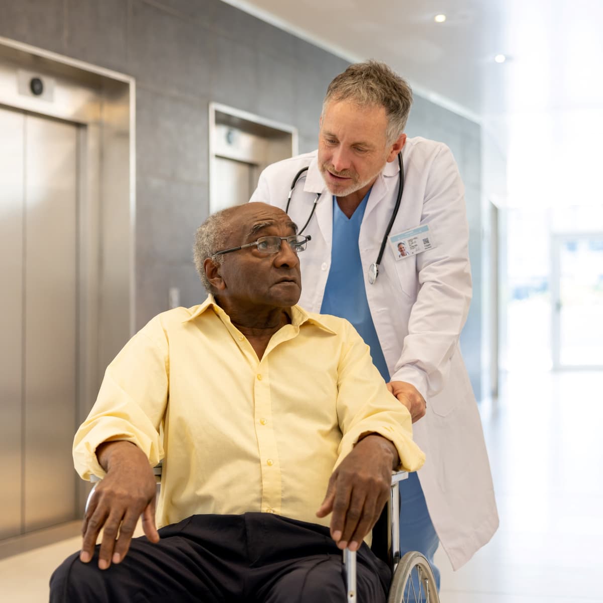 A man being pushed in a wheelchair by a doctor.