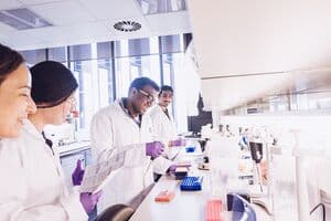 A group of researchers in a lab, working and smiling.