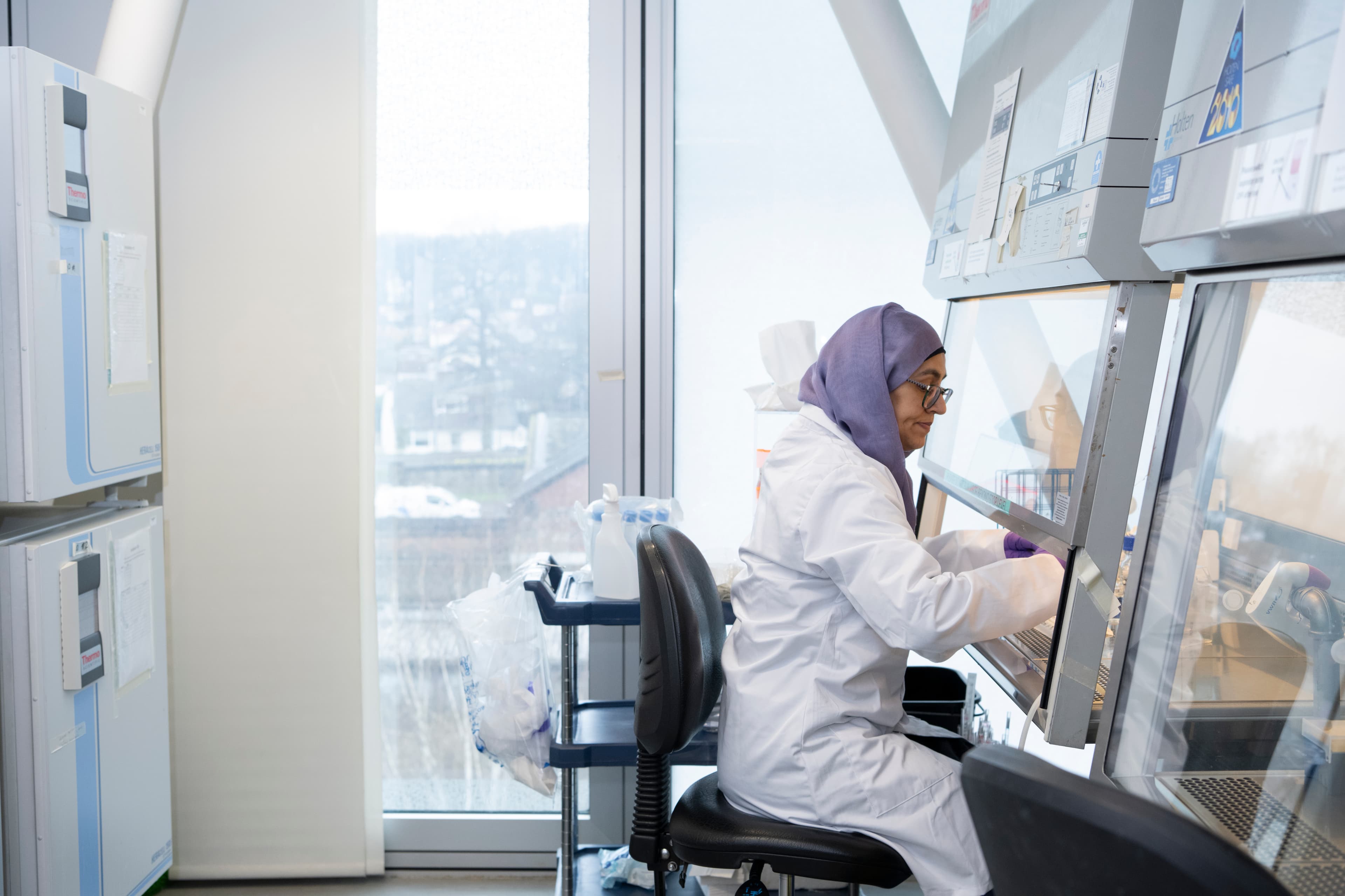 A researcher working by a fume hood in a lab.