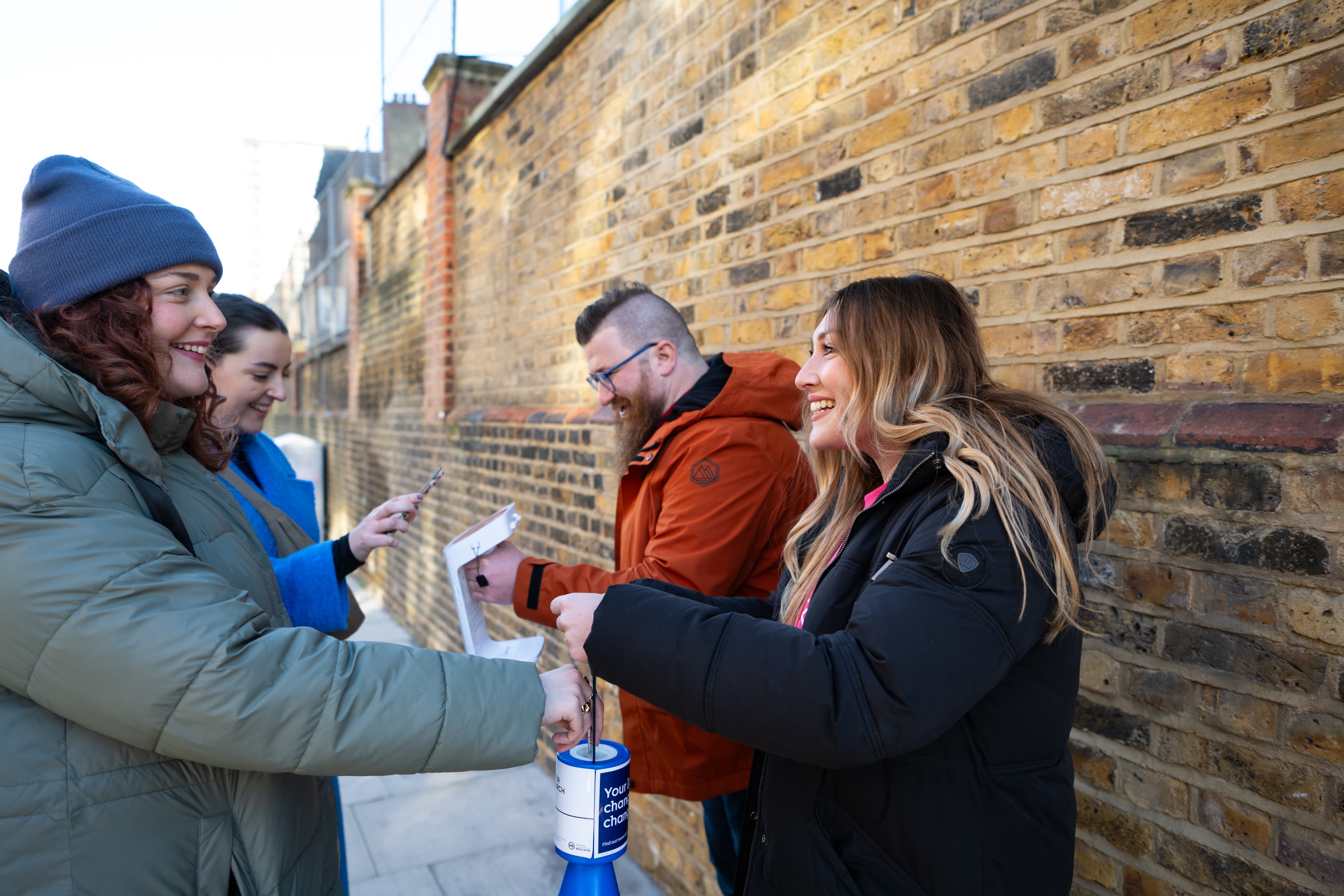 An image of people making a donation by putting money into a collection bucket.