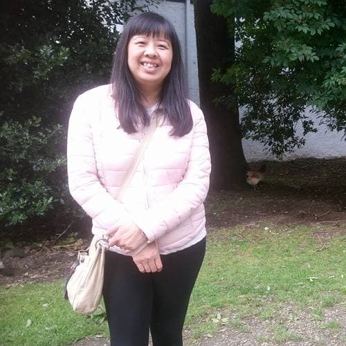 A lung cancer patient, Jennifer, standing and smiling in a park.