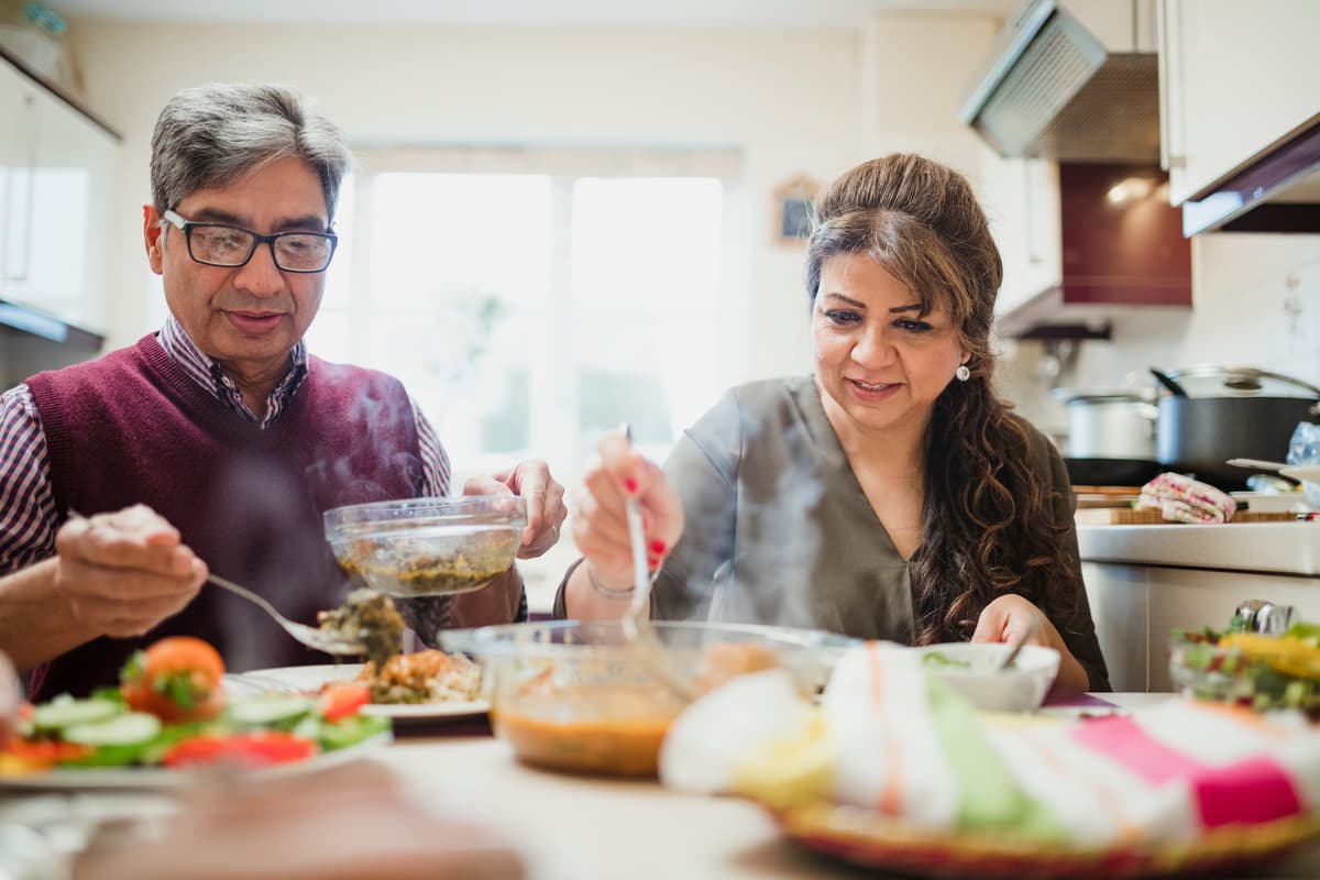 Mature couple are enjoying a homemade curry with salad at home..