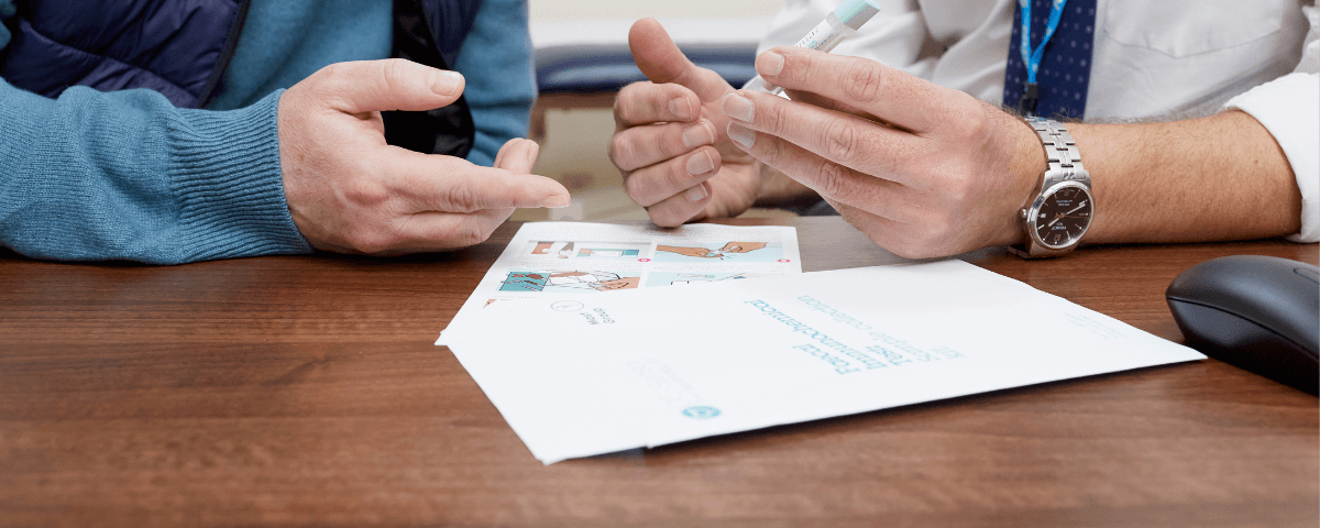 This photo shows a GP talking to a patient about a symptomatic Faecal Imunochemical Test (FIT) kit from England.