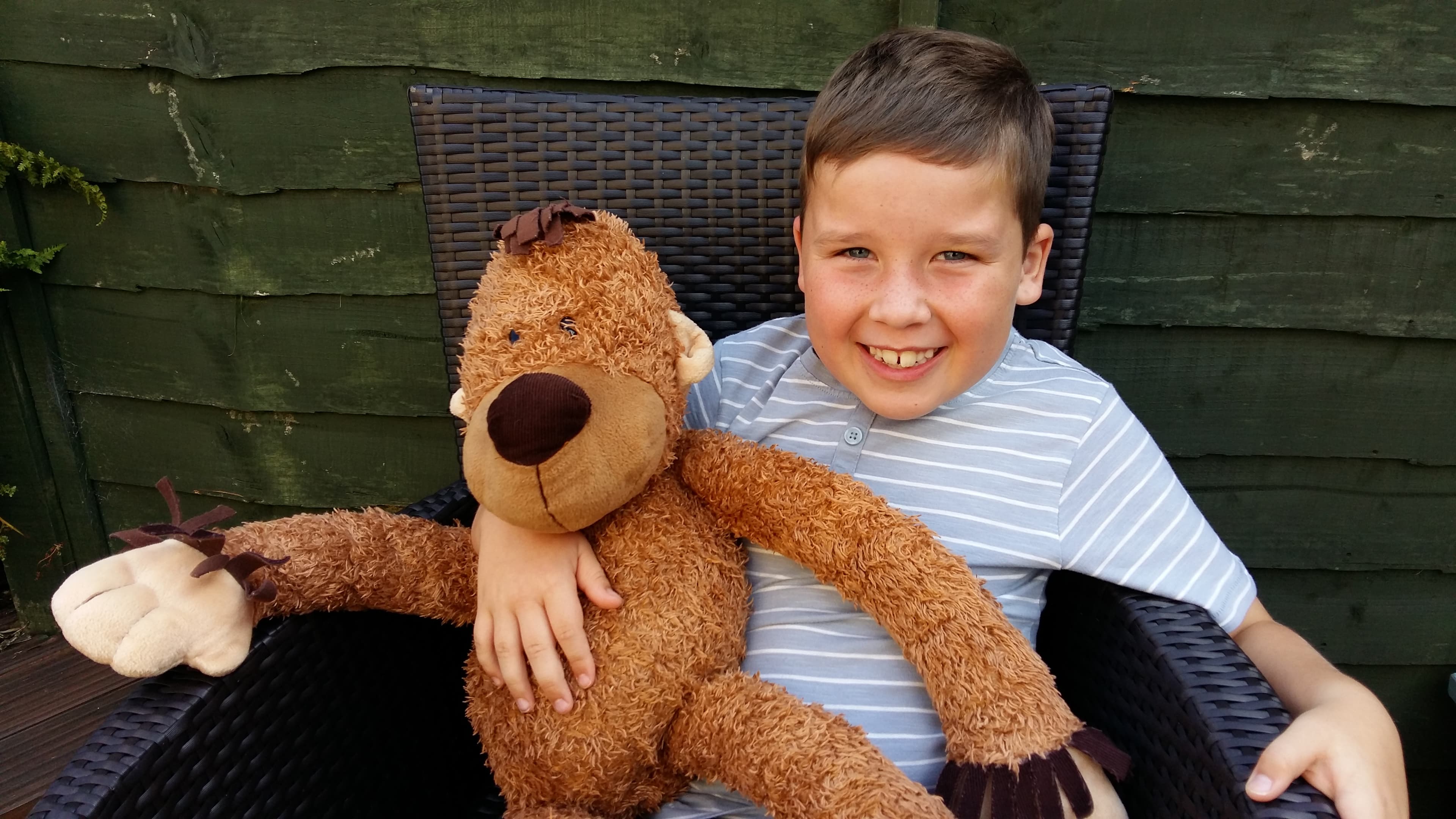 Rhys - a brain and nerve cancer patient, smiling and holding a teddy.