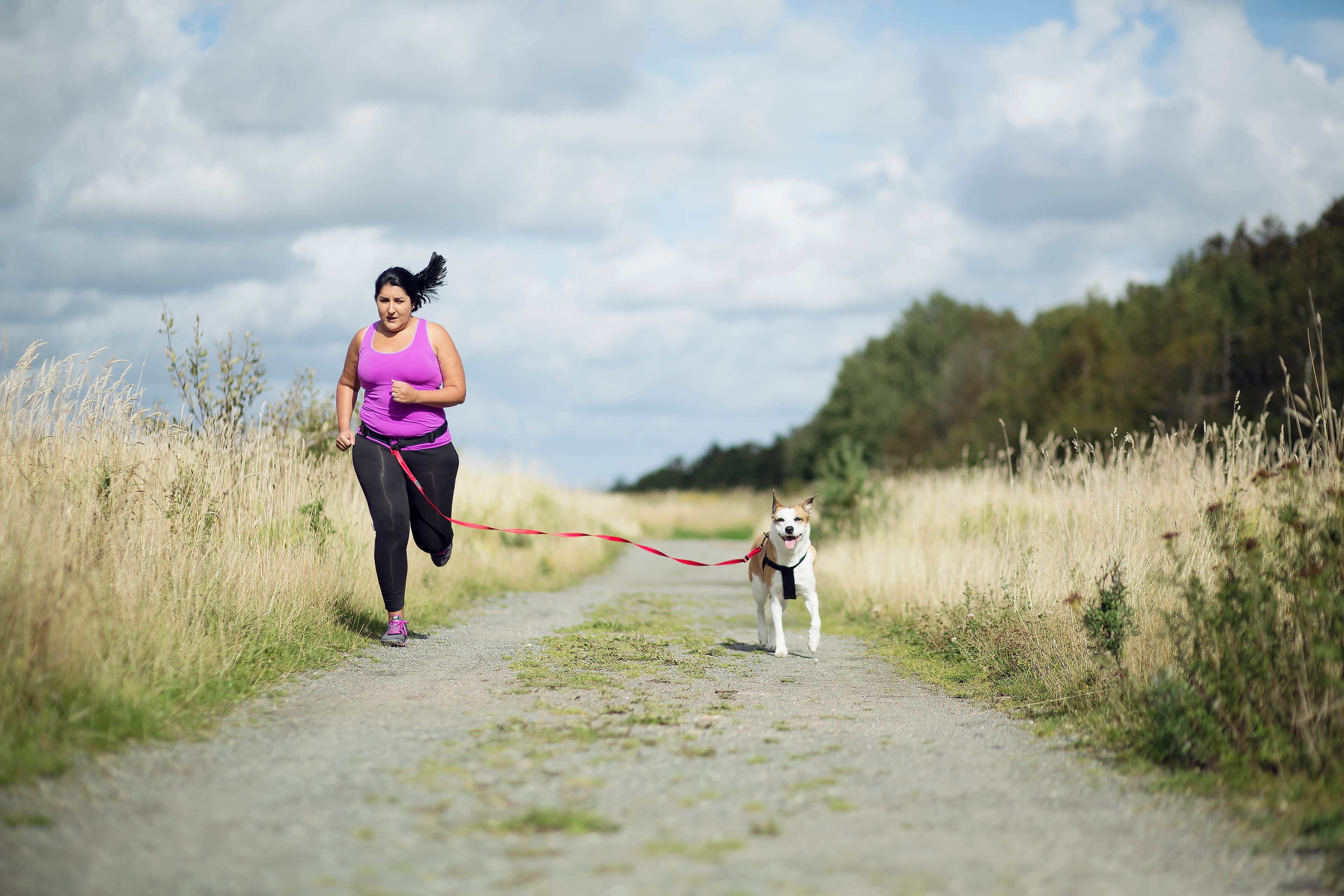 A person running outdoors with a dog.