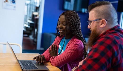 A photo of two people looking at a laptop