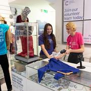 Three volunteers in a CRUK shop, working near the till