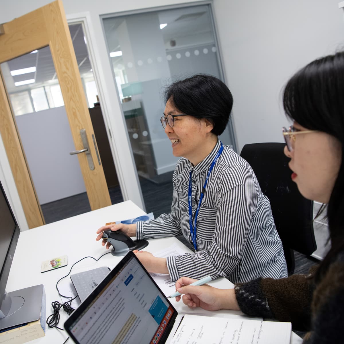 Two researchers looking at a computer screen at a desk.