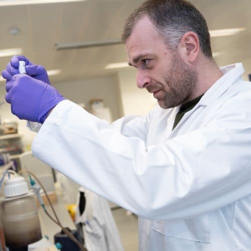 Image of a researcher holding up a pipette in a lab.